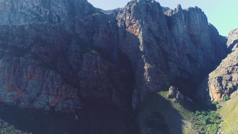 Luftaufnahme-Nach-Oben-In-Richtung-Zerklüfteter-Sandsteinberge-Mit-Wasserfall