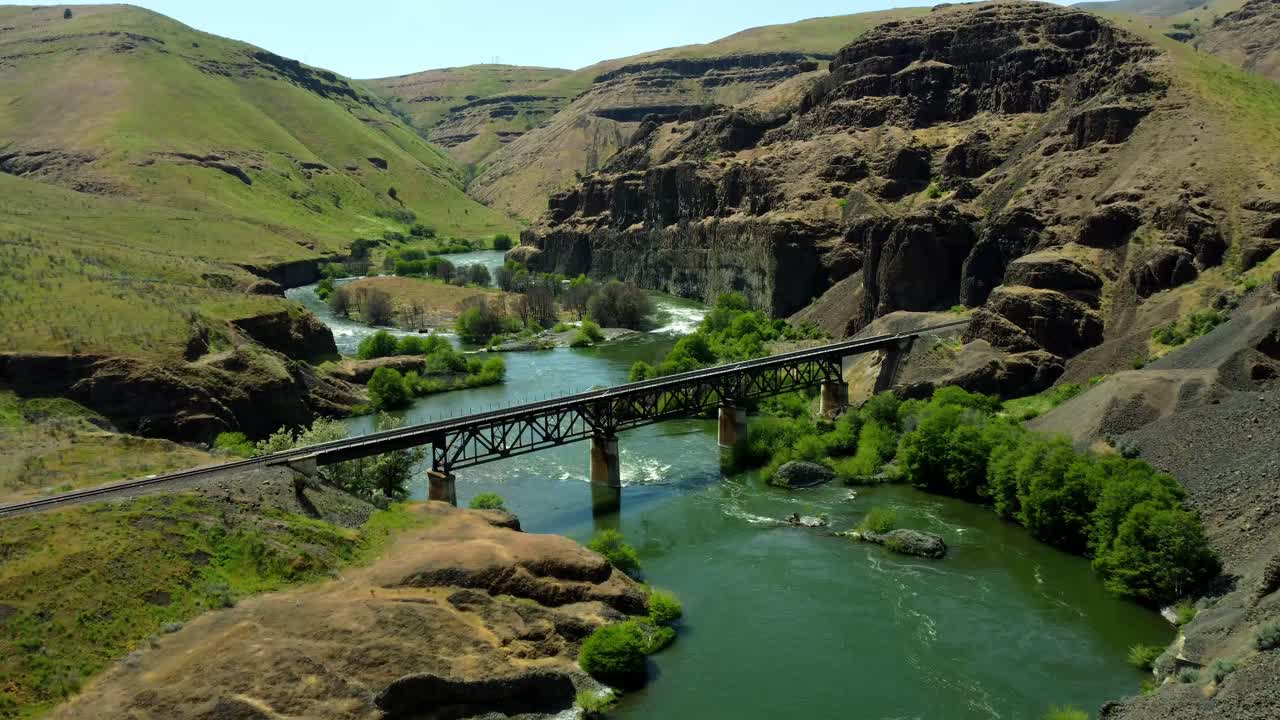 US, Oregon, Maupin, Deschutes River, 2025-05-08 - Drone view on the Deschutes River of a train bridge at Twin Crossings which is two bridges and a tunnel. In north central Oregon in spring