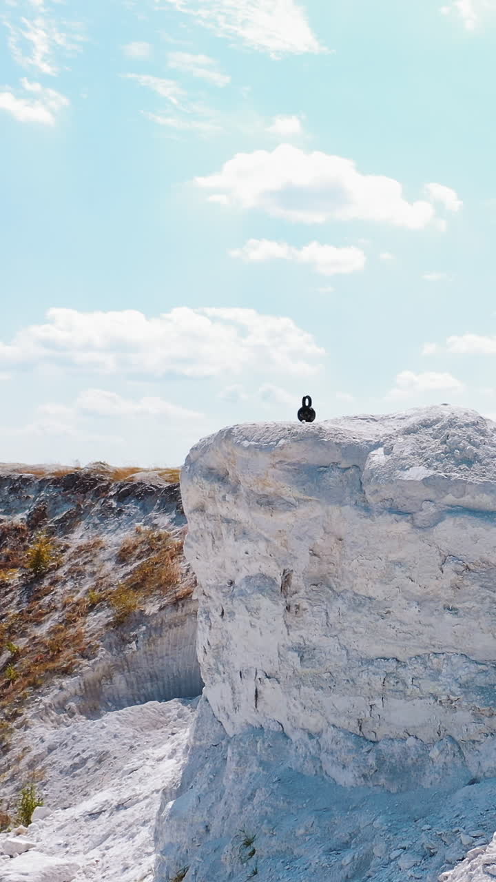 Man Resting After Workout. Aerial view of athletic man resting after hard training in the mountains. Vertical video