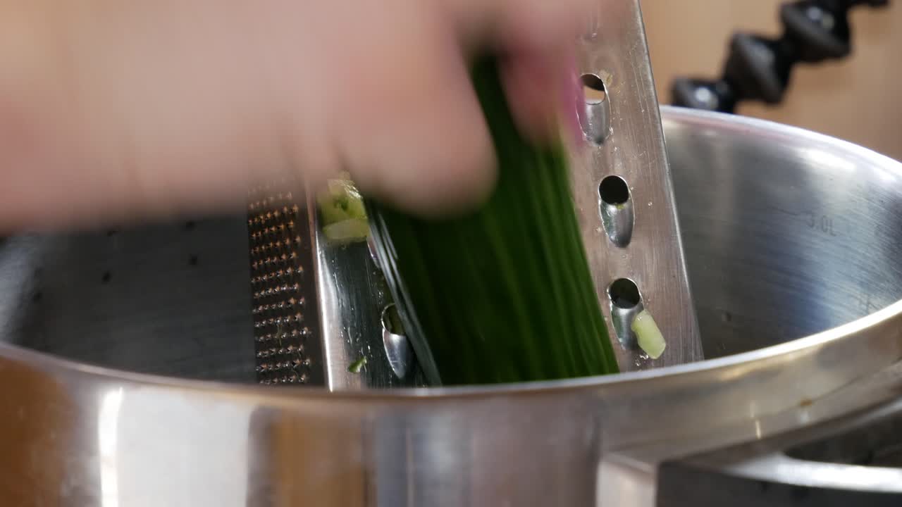 Female using grate for fresh cucumber directly to stainless steel pot