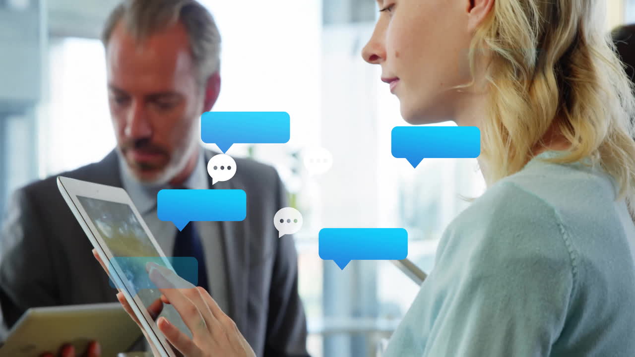 Woman tapping tablet in office while man reviewing device, displaying chat bubbles and tech data