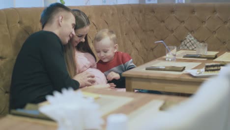 father and toddler boy run hands on pregnant mother belly