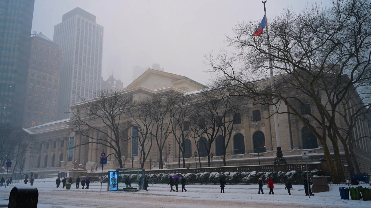 New York, USA, 9 gennaio 2026: Facciata della New York Public Library con pedoni sotto la neve che cade. Vista laterale di un classico edificio in pietra, alberi spogli e passanti sul marciapiede innevato della Fifth Avenue.