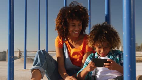 Mother-and-son-using-phone-at-playground