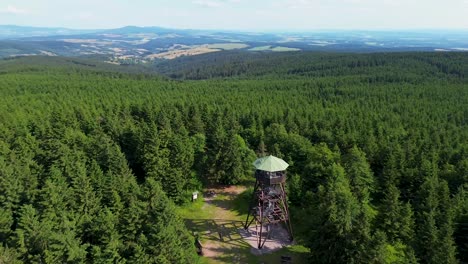 drone view as it flies over the trees and rotates near the lookout tower on the mountains with the valley in the background