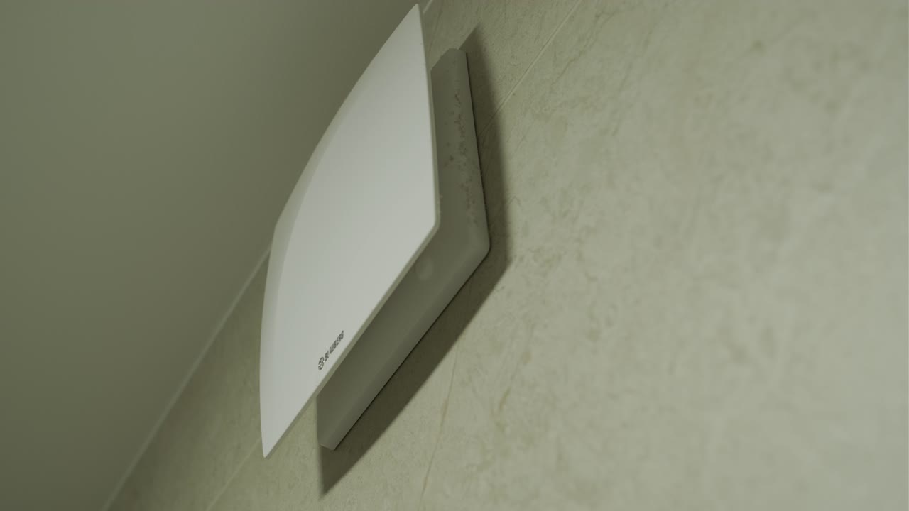 White Ventilation Fan Operating on a Tiled Bathroom Wall