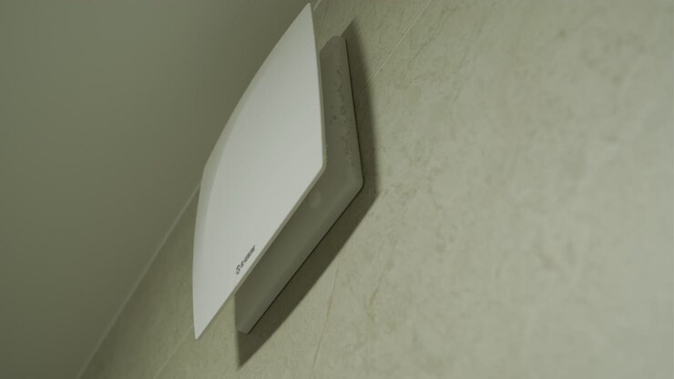 White Ventilation Fan Operating on a Tiled Bathroom Wall
