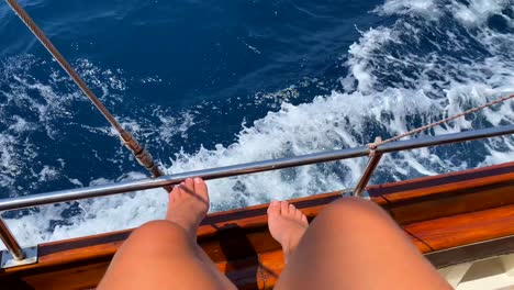 Piernas-Y-Pies-Femeninos-En-Un-Velero-De-Madera-Y-Olas-Del-Mar,-Divertidas-Vacaciones-De-Verano,-Barco-En-Movimiento,-Vacaciones-Soleadas,-Toma-De-4k