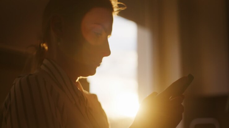 silhouette di una donna che naviga sui social media alla luce del sole