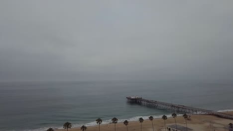 Pier-and-Pacific-Ocean-view-Behind-Palm-Trees-on-Gray-Cold-Morning