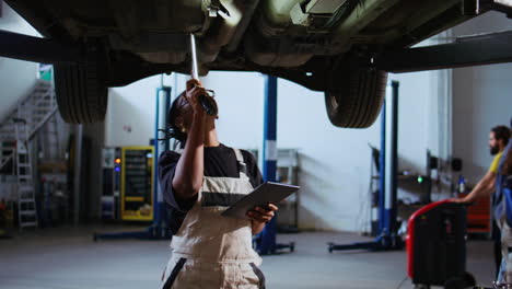 engineer uses light to check car on lift