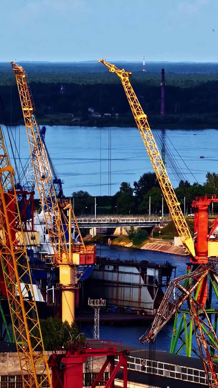 Side-on vertical social ratio aerial video of shipping cranes at the docks in Riga, Latvia. Produced in 1080x1920 and with Rec709 color.