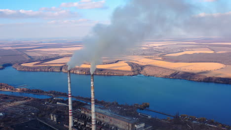 view from the drone at the old aged weathered tall industrial factory chimney with smoke over it. cloudy sky background