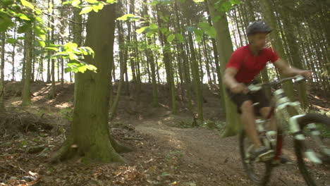 Slow-Motion-Shot-Of-Man-Riding-Mountain-Bike-Through-Woods