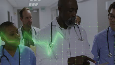 animation of heart rate monitor over team of diverse doctors, health workers discussing at hospital