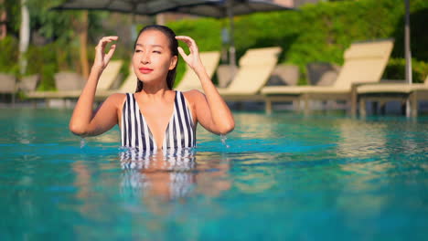 Mujer-Asiática-Moderna-Relajándose-En-La-Piscina-Mirando-A-La-Cámara-Slomo