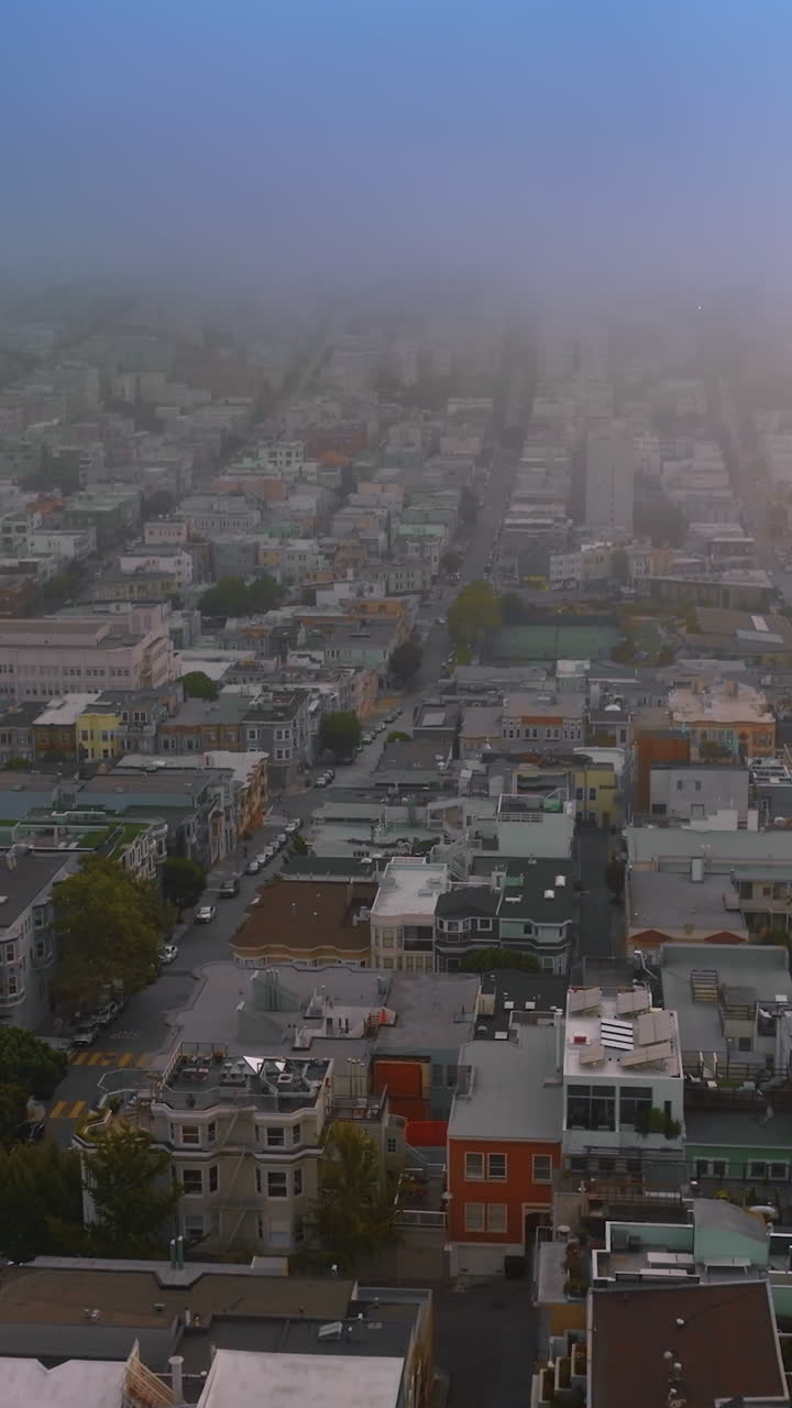Flying over the residential area of beautiful San Francisco at sundown. Thick fog covering quickly the city. Top view. Vertical video