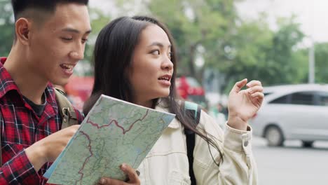 Handheld-view-of-young-couple-with-backpack-reading-map