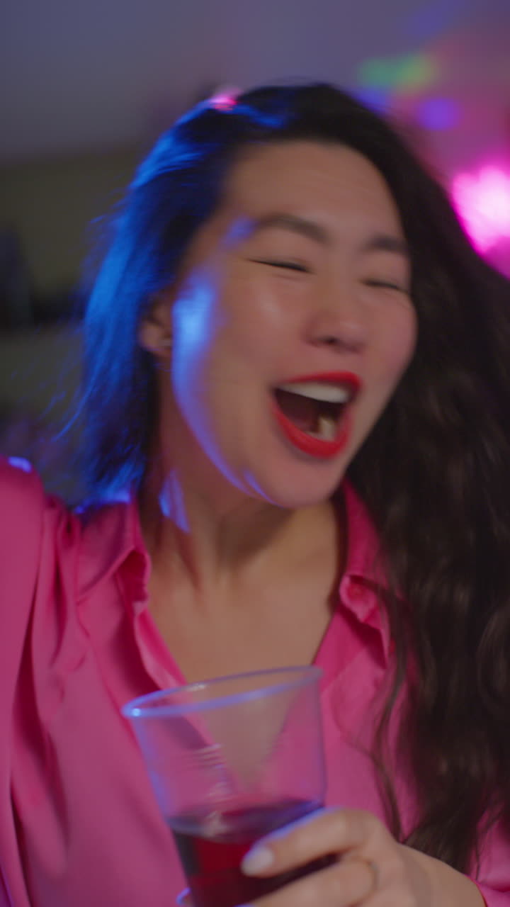 video vertical de mujer de cabello largo divirtiéndose bailando y bebiendo alcohol en la fiesta de la casa 1