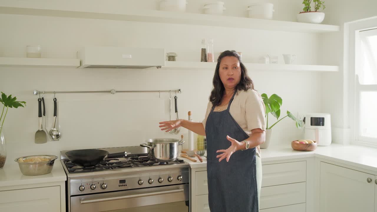 Cuoche con i grembiuli dopo una vivace chiacchierata in cucina, la donna con il grembiule blu posa una pentola spiegando i passaggi.