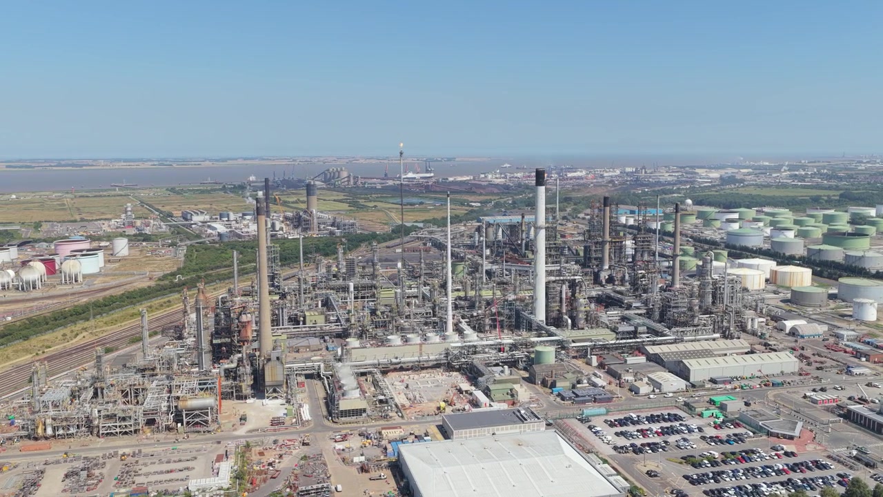 Vasto paesaggio industriale che mostra il complesso della raffineria di petrolio a North Killingholme di giorno, con grandi serbatoi di stoccaggio, strutture di lavorazione, condotte e infrastrutture ferroviarie vicine.