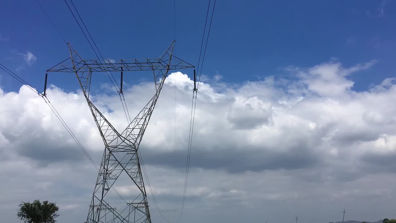 Timelapse of Moving clouds above the high tension electric tower in Paddy fields of India