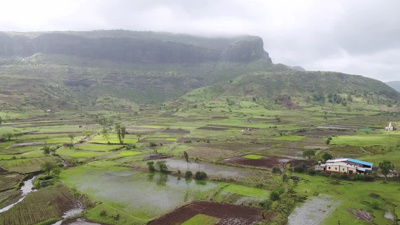 Nuvole di pioggia sopra la scogliera rocciosa e i campi verdi a Trimbakeshwar, India, durante il monsone - drone aereo