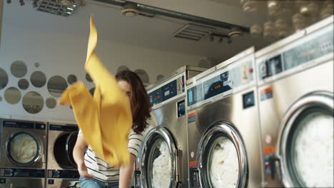 cheerful young beautiful woman having fun and laughing as throwing clothes from basket at laundry service