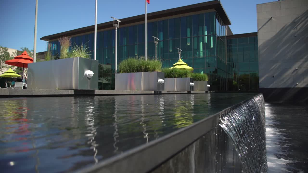 Biblioteca Pública de Whitby con cascada sobre un muro de piedra en la Plaza del Jardín Botánico con mástiles de banderas