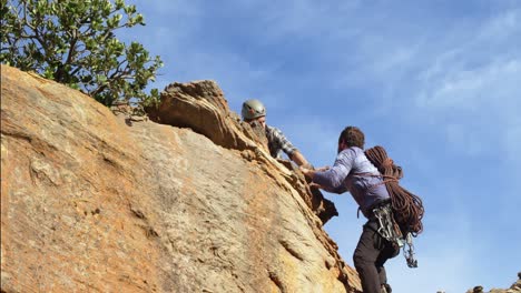 man helping his friend to climb a cliff 4k