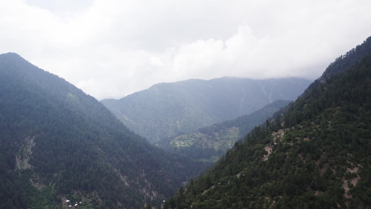 Forested mountain slopes converge in a misty valley junction in the Himalayan region of Kashmir. Kashmir, India