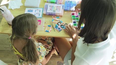 mother and daughter beading together