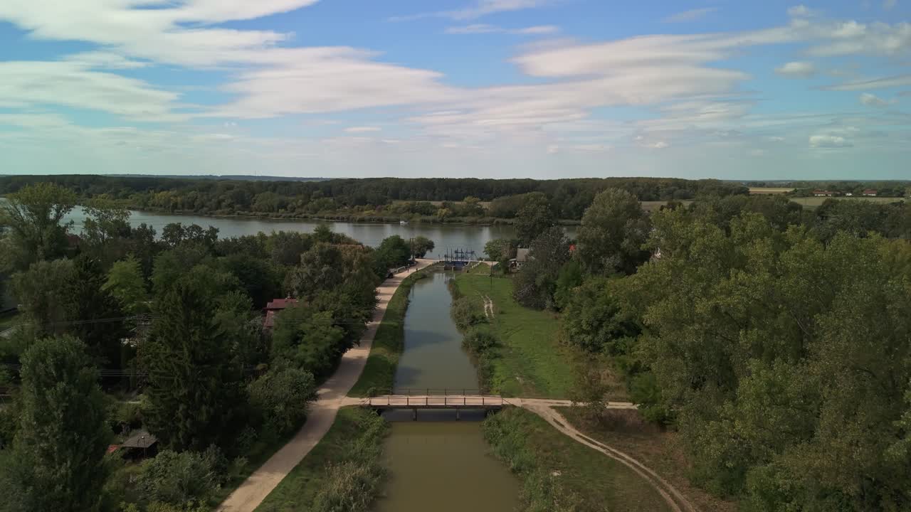 Vista aerea ascendente sul canale navigabile a Dömsöd, in Ungheria, che rivela il rigoglioso paesaggio fluviale mentre il corso d'acqua conduce verso il fiume Danubio all'inizio dell'autunno