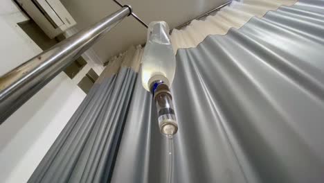 intravenous drip with a hospital curtain in the background - hospital room