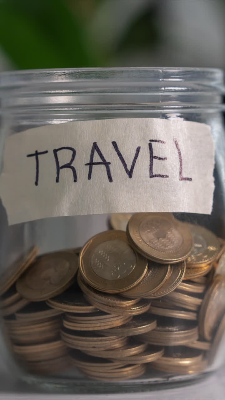 Time-lapse Saving Money Concept For Travel. Coins into Glass Jar on White Desk. Vertical