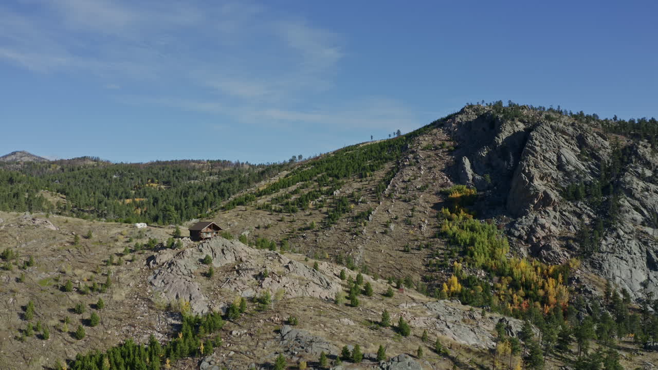 cabina de montaña escénica remota en órbita aérea en afloramiento rocoso, 4k
