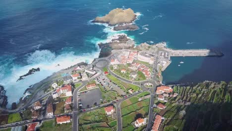 flying over porto moniz town, madeira island, portugal famous tourist vacation destination at sunset aerial view of natural volcanic swimming pools and huge waves crashing into the coastline