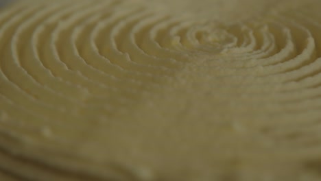 Extreme-close-up-of-the-top-of-a-spinning-cake,-decorated-with-a-spiral-frosted-design