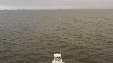 An-aerial-view-of-a-small,-white-fishing-boat-speeding-in-the-deep,-green-Atlantic-Ocean-by-Long-Island,-NY