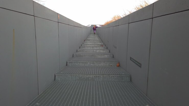 A young girl in a purple jacket ascends the modern metal stairs of the Museum of Ethnography in Városliget, Budapest. A cinematic shot capturing childhood curiosity within minimalist architecture