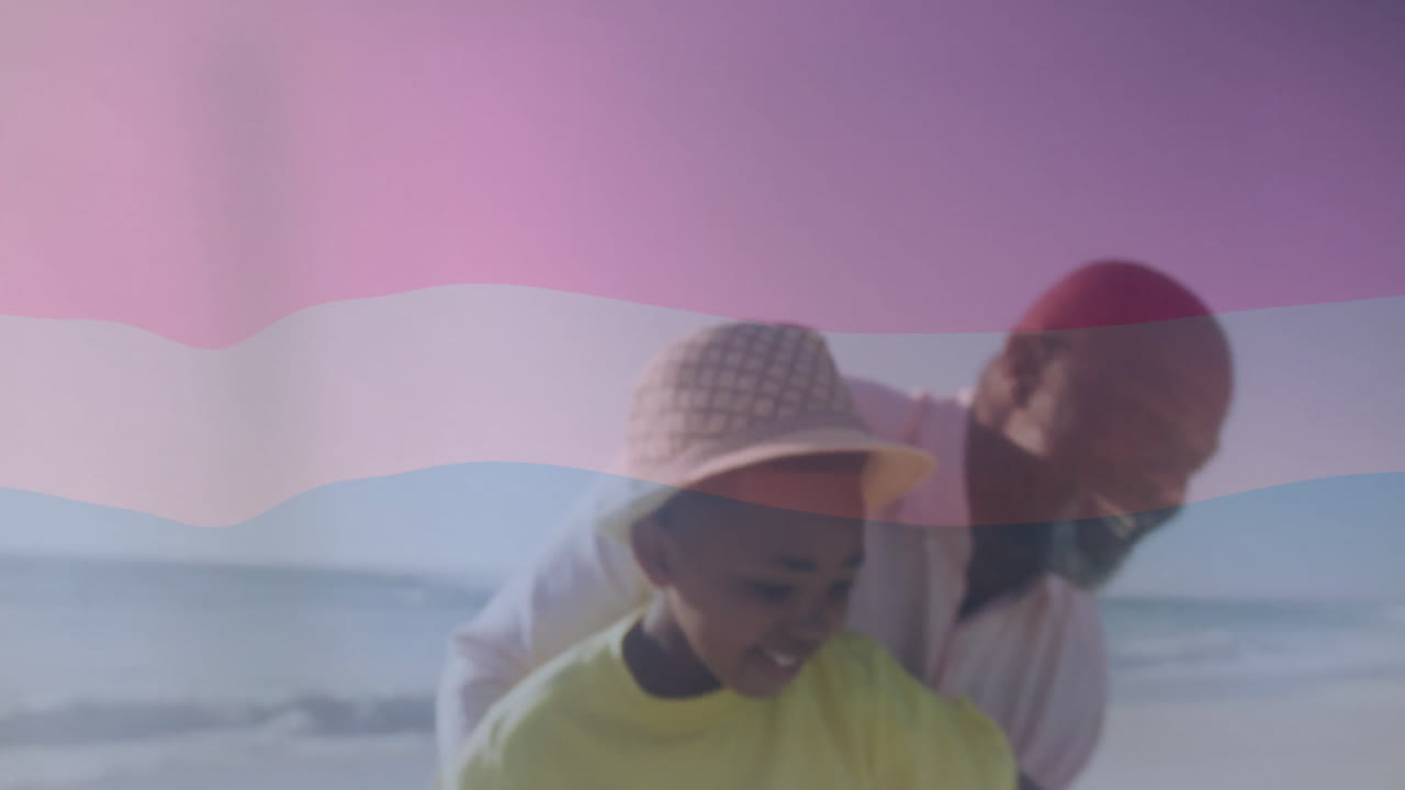 Playing on beach, father and child with animation of transgender pride flag