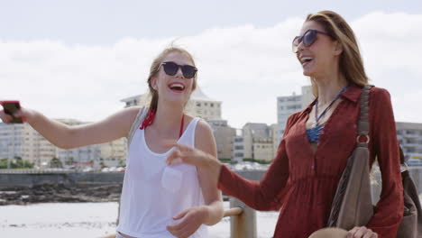 two young women pointing at view on beach promenade enjoying carefree vacation