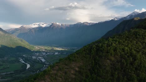 Una-Toma-Aérea-Dinámica-Que-Se-Mueve-Sobre-Una-Montaña-Que-Se-Dirige-Hacia-Los-Pueblos-De-Villadossola,-Domodossola-Y-El-Puerto-Simplon-Rodeado-De-Montañas-Y-Ríos-Cercanos