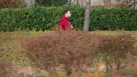 Hombre-En-Forma-Corriendo-En-Un-Sendero-Del-Parque-De-La-Ciudad---Vista-De-Perfil-De-Tiro-De-Seguimiento