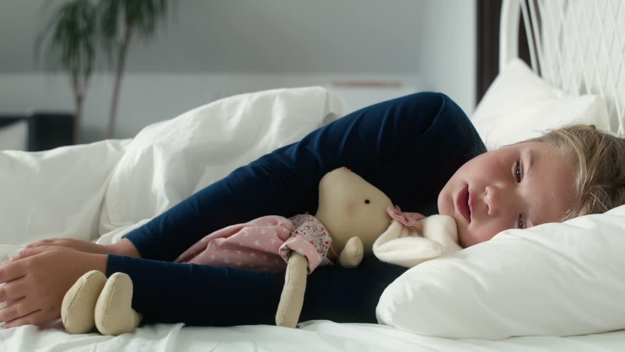 병든 초등학생 소녀가 침대에 누워서 독감에 걸렸어요.