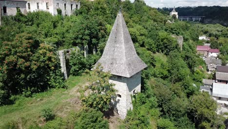 aerial pan left towards kushnirska tower surrounded with greenery and old buildings at kamianets podilski,ukraine.