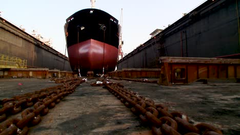 crane panning rtl and tilting up shot of an oil supertanker in dry dock. shot from floor level