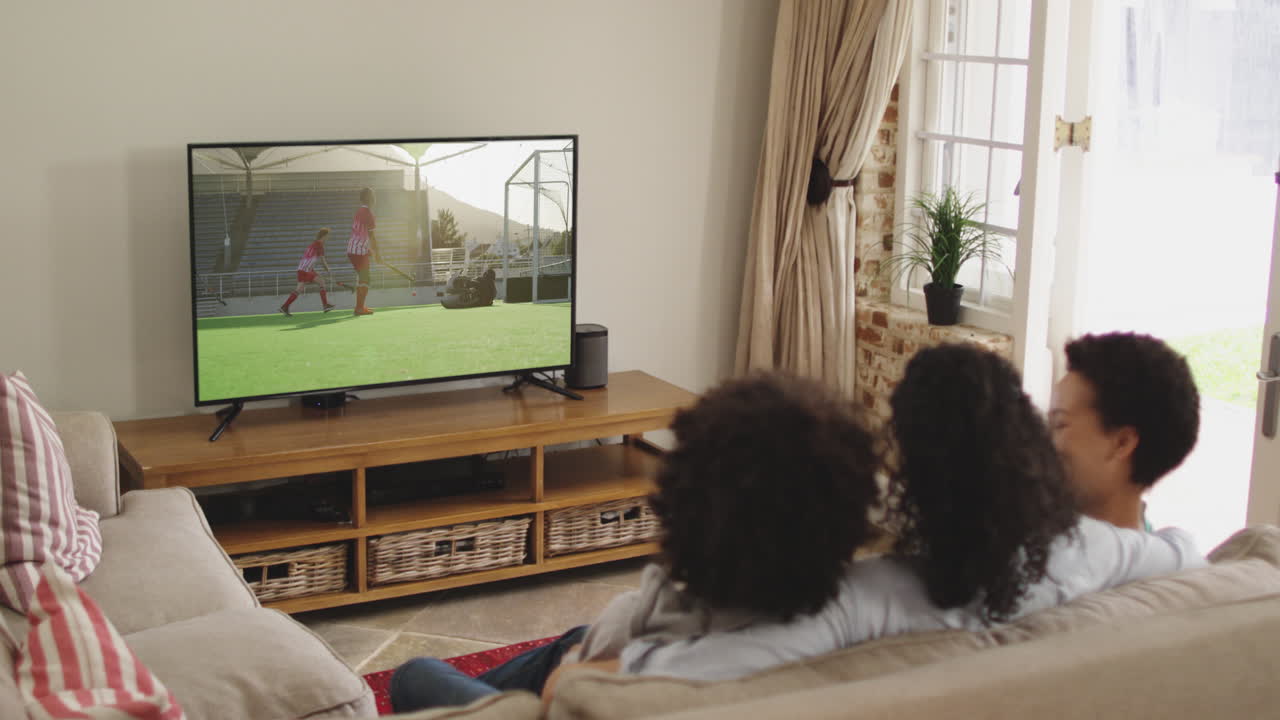 Famiglia felice seduta a casa insieme che guarda una partita di hockey in TV