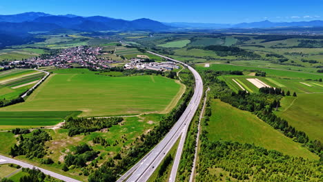 scenic highway and countryside. aerial view showcasing a highway winding through lush green fields near a small town in a picturesque valley