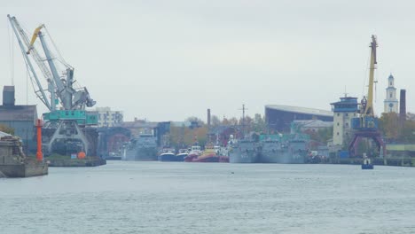 View-of-Port-of-Liepaja-with-port-cranes-and-moored-ships-on-overcast-day,-view-from-South-Pier,-distant-wide-shot